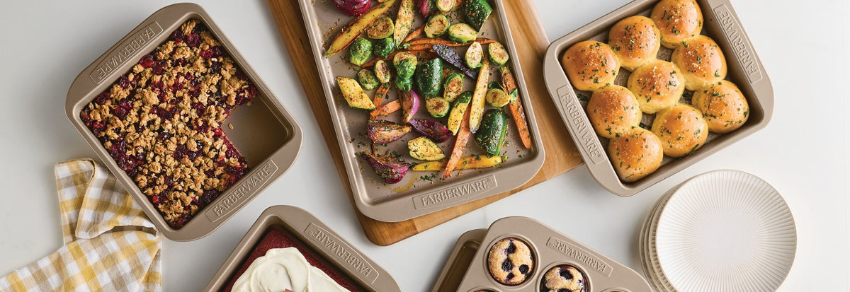 A top-down styled flat lay of brown nonstick baking pans holding prepared foods, with white plates and a yellow-and-white check cloth on a light surface. The pans are branded with the Farberware brand name.