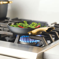 Broccoli and chili peppers sizzle in the Forged Induction Ceramic 8.25-Inch Frying Pan on the gas stove.