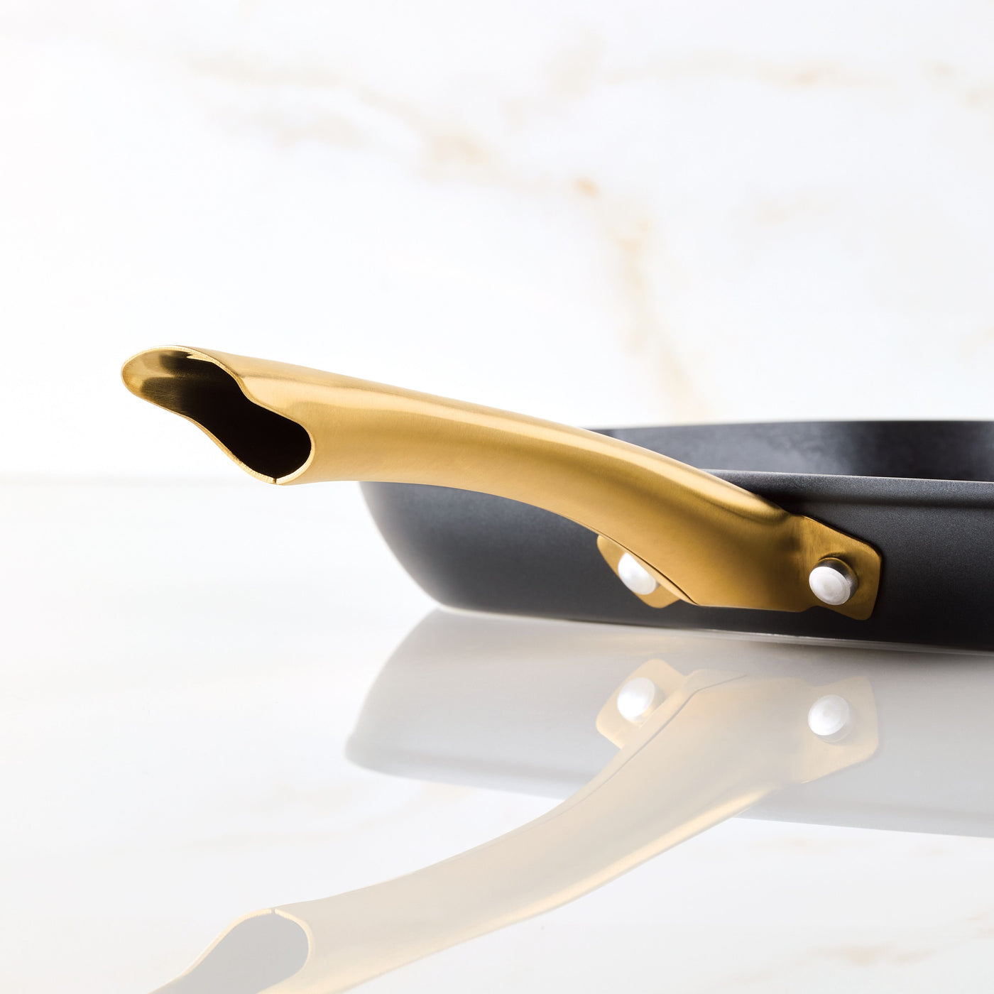 Close-up of the Forged Induction Ceramic 11-Inch Square Grill Pan with a golden handle on a marble surface, showcasing its induction-ready ceramic nonstick coating.