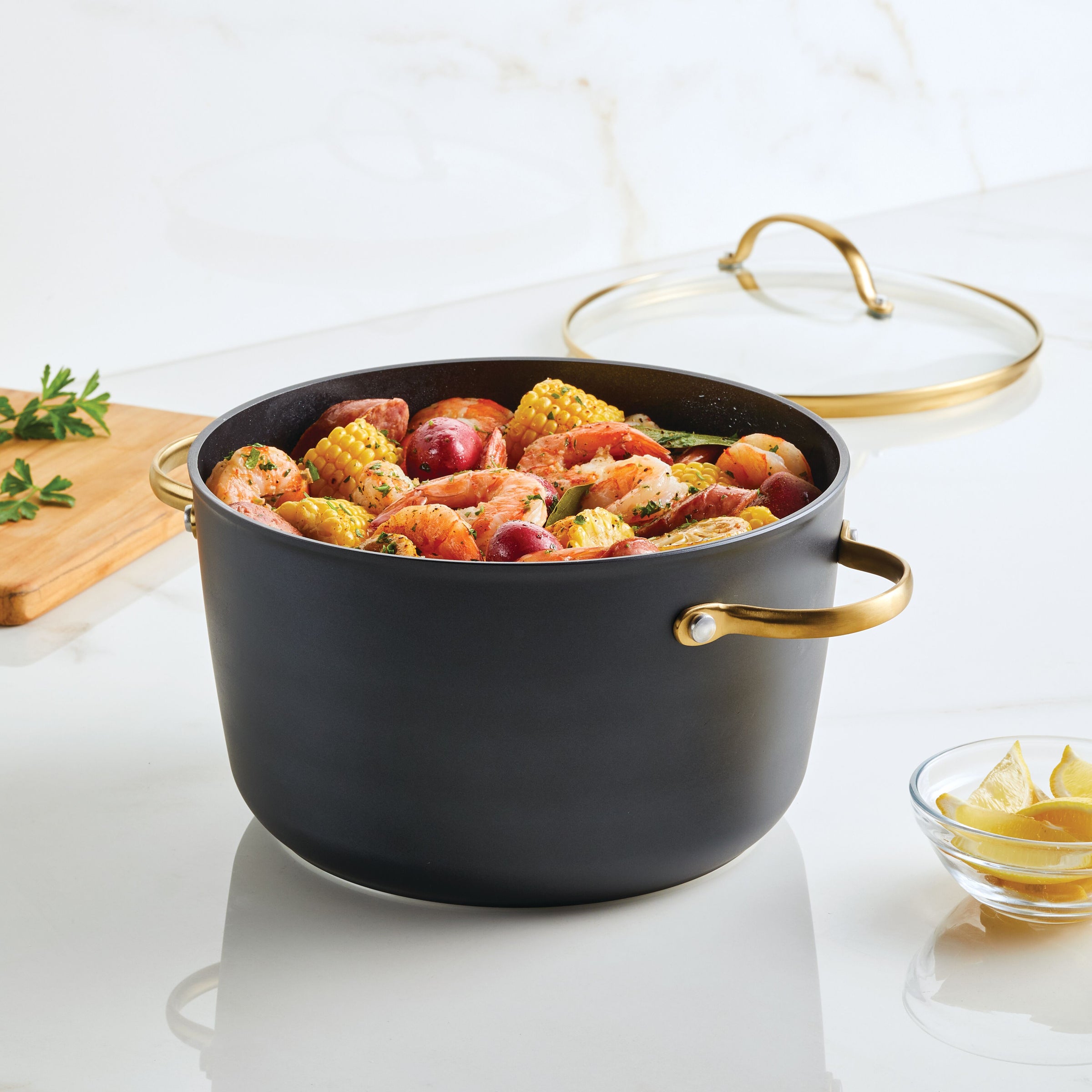 A pot of mixed seafood boil with corn and potatoes sits steaming on the kitchen counter, cooked to perfection in a Forged Induction Ceramic 6-Quart Stockpot With Lid.