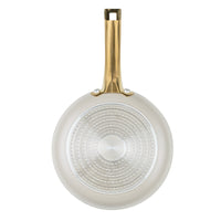 A bottom view of the Forged Induction 8.25-Inch Frying Pan's exterior base. The silver, induction-compatible plate features a textured pattern of concentric dots for efficient heat conduction. The pan’s taupe exterior and the underside of the gold-tone handle, including its double-rivet attachment, are clearly visible.