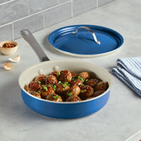 The 2.75 Quart Ceramic Nonstick Saute Pan is showcased with meatballs garnished with green herbs, highlighting its durable design. Next to it are the included lid and a towel, both reflecting a modern and elegant style.
