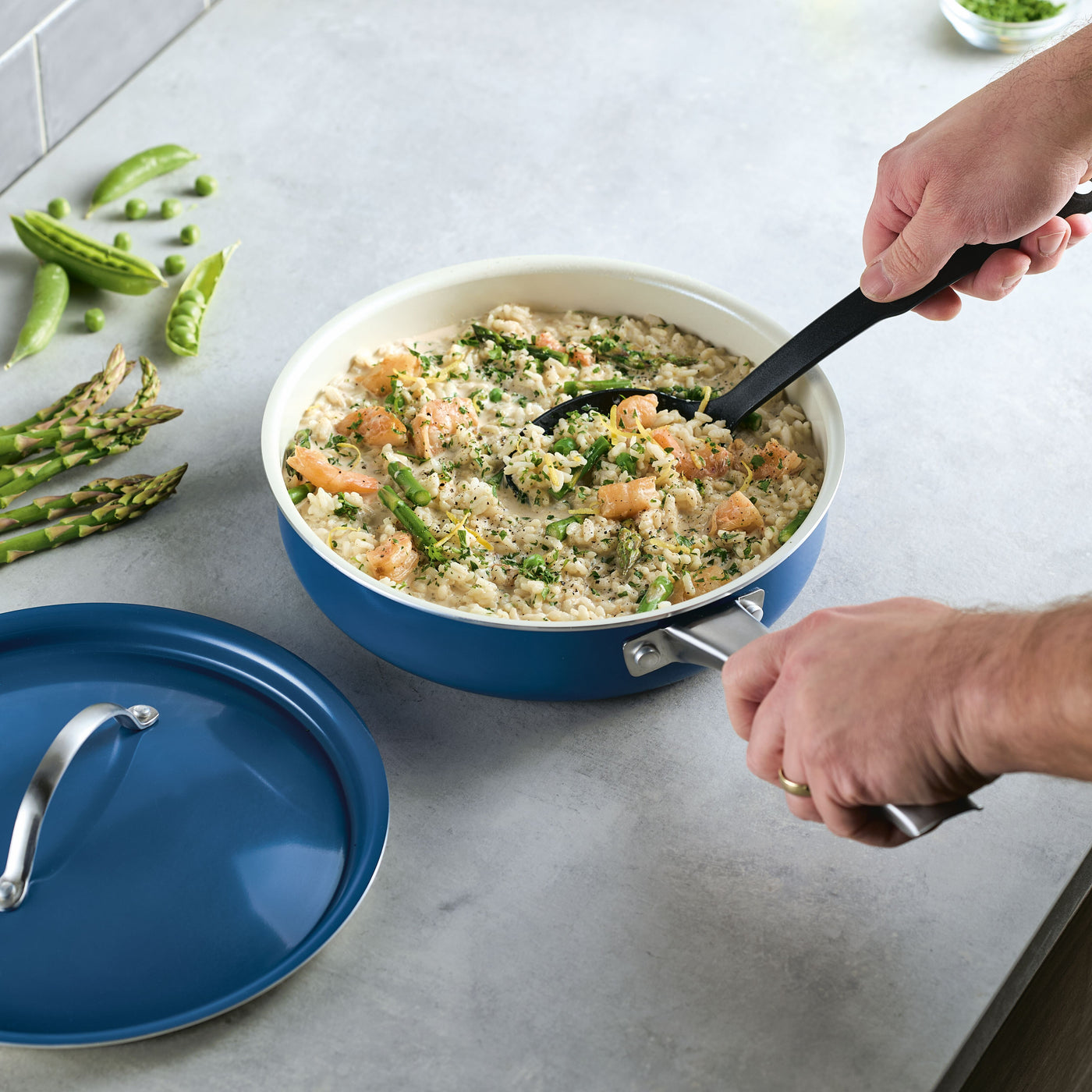 A person stirs risotto with vegetables and shrimp in a 2.75 Quart Ceramic Nonstick Saute Pan with Lid, highlighting the modern and elegant design of healthy ceramic nonstick cookware.
