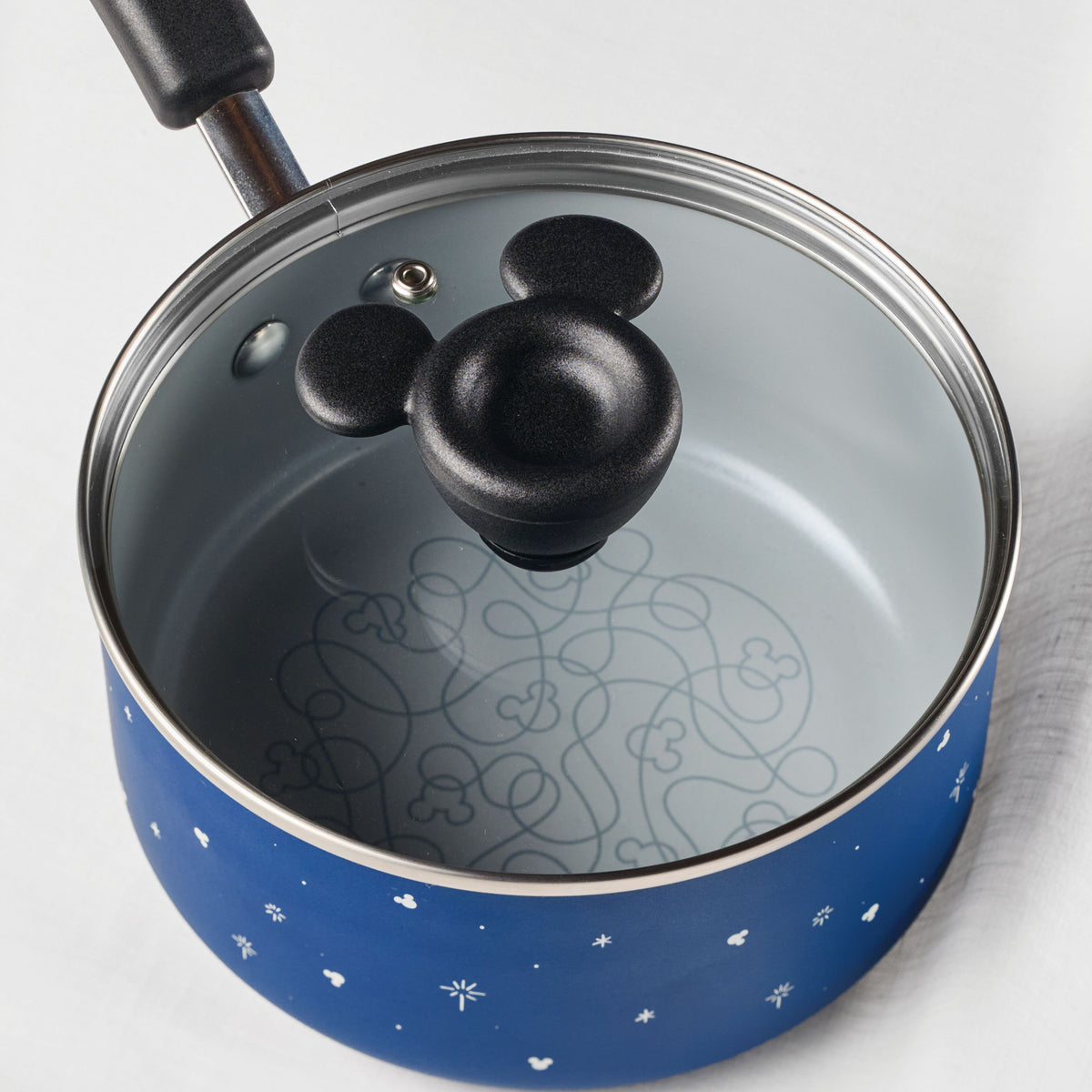 Blue saucepan with mouse-shaped lid handle and decorative interior pattern.