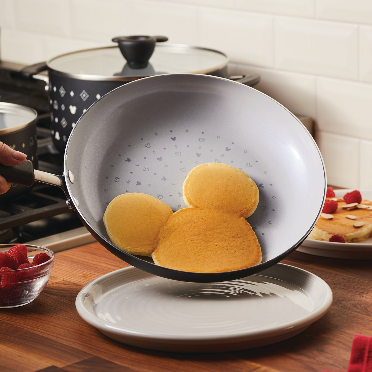 Pancake shaped as a cartoon mouse head in a frying pan over a plate.