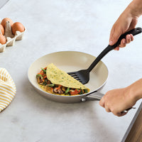 Person folding veggie omelet in Ceramic Nonstick Frying Pan Twin Pack.
