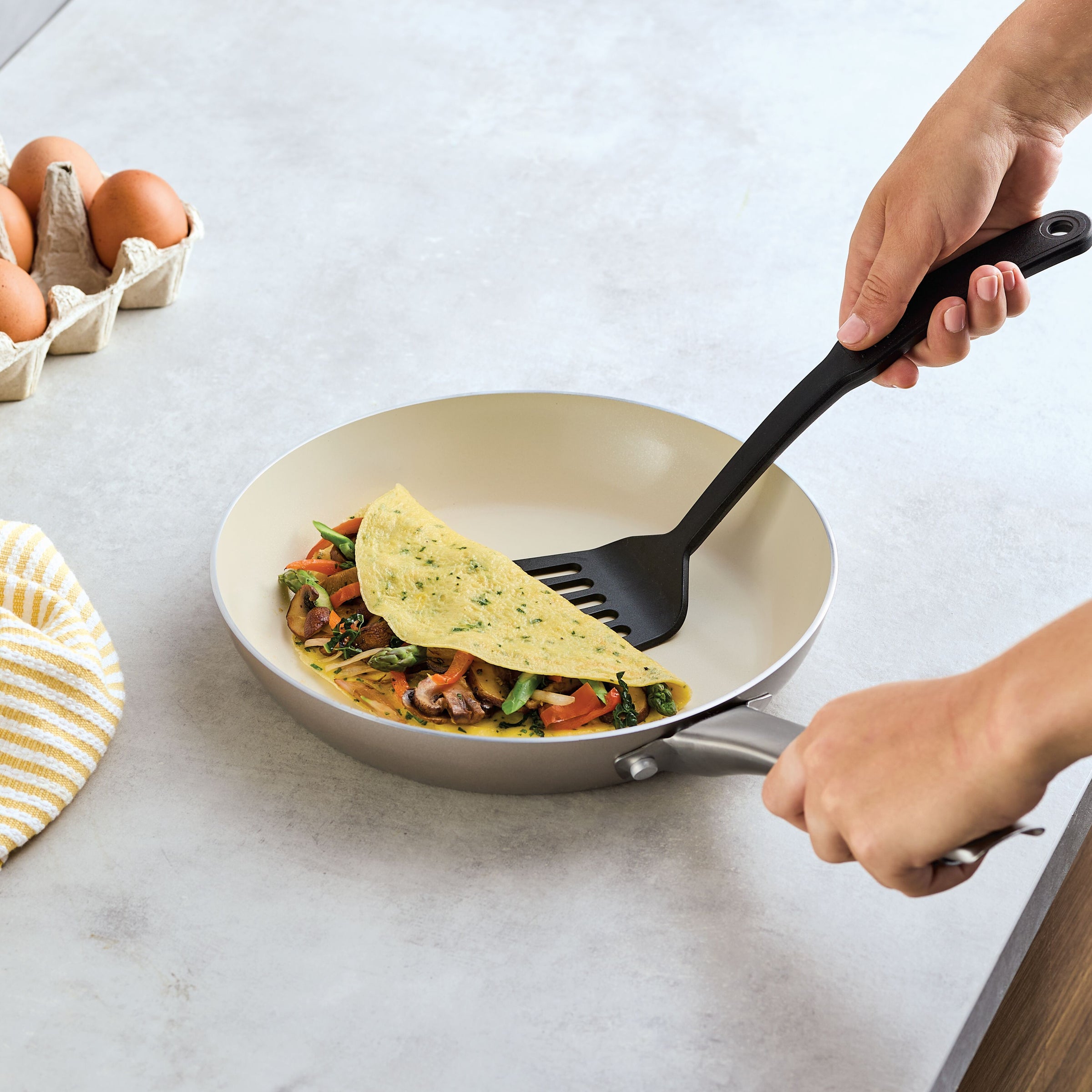 Person folding veggie omelet in Ceramic Nonstick Frying Pan Twin Pack.