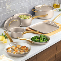 The Radiant Nonstick 12-Piece Cookware Set, featuring pans, pots, and a griddle with gold accent handles, elegantly rests on the kitchen counter.