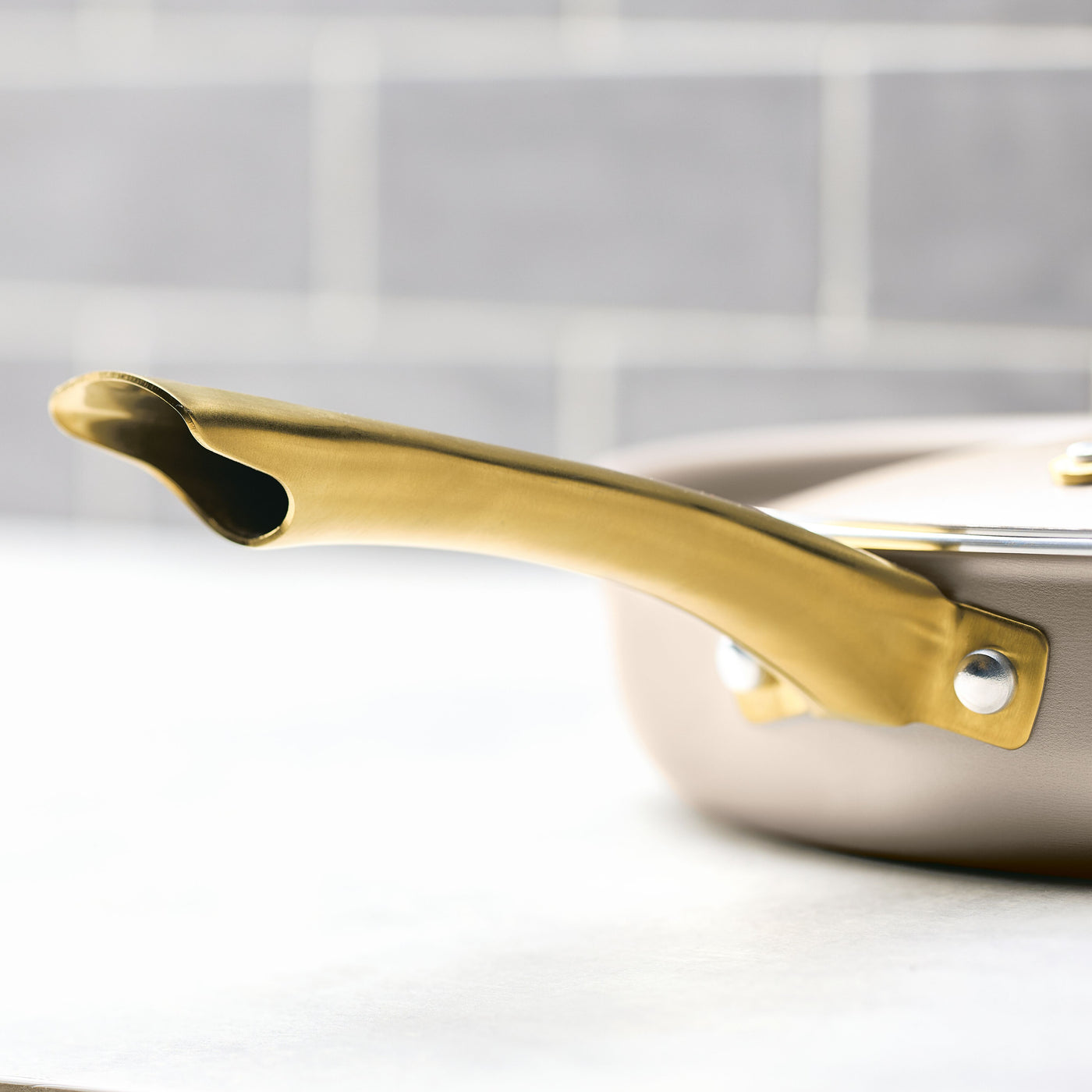 Close-up of a gold accent handle on the Radiant Nonstick 2.75-Quart Saute Pan With Lid, resting elegantly on the stove.
