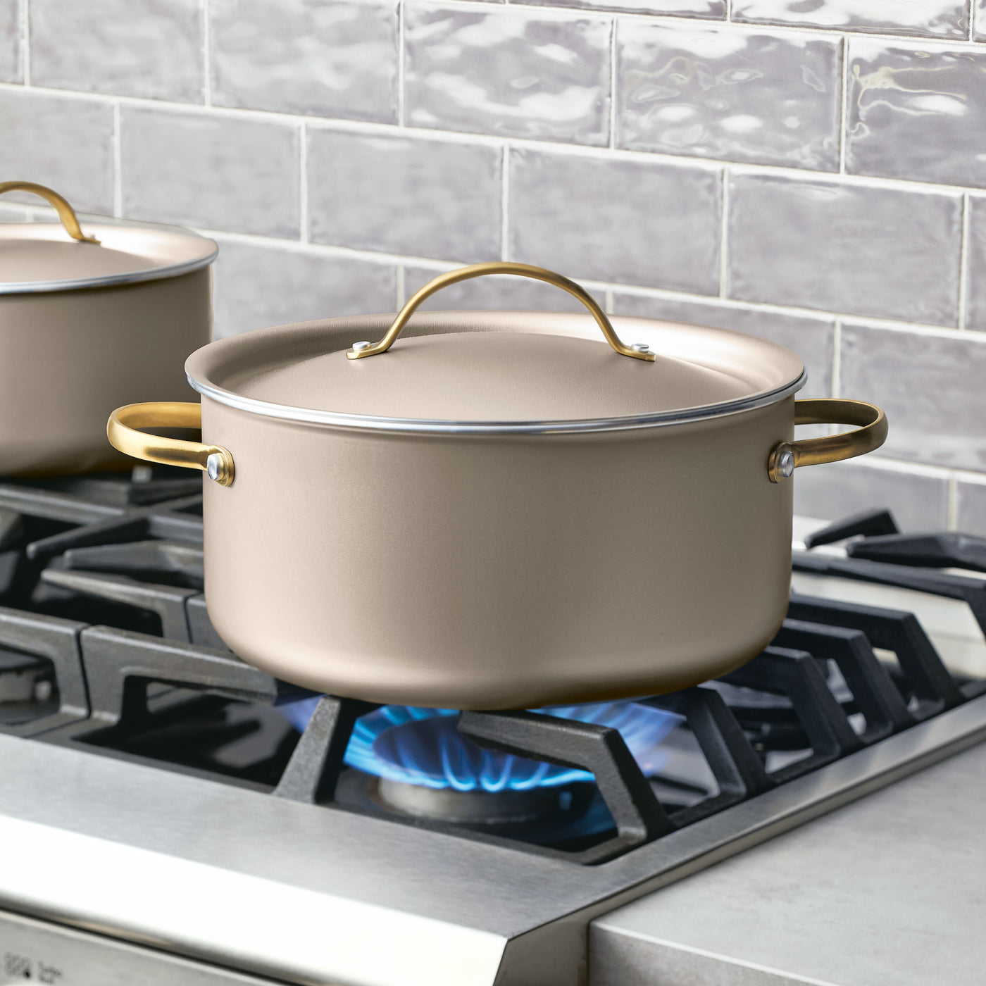 The Radiant Nonstick 5.5-Quart Dutch Oven With Lid sits on a lit gas stove burner, ensuring even heat distribution in the kitchen setting.