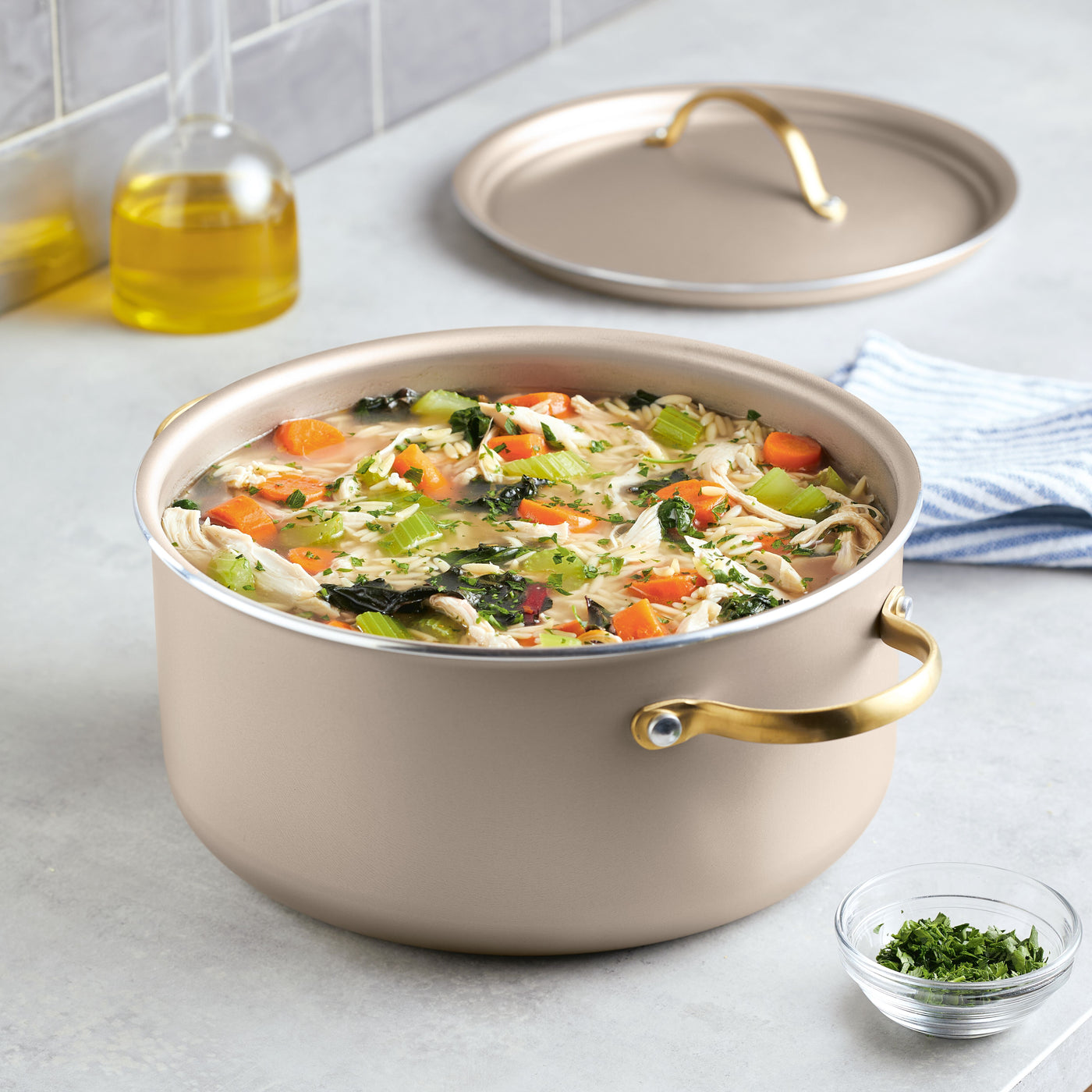A Radiant Nonstick 5.5-Quart Dutch Oven With Lid brims invitingly with vegetable soup, its exceptional heat distribution ensuring every herb-infused spoonful is perfectly cooked. On the side, a small bowl of garnish promises to elevate each serving.