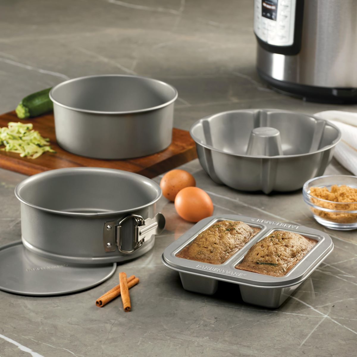 The 4-Piece Nonstick Specialty Bakeware Set sits elegantly on the kitchen counter, surrounded by delectable baked goods and essential ingredients, ready to inspire your next culinary creation.