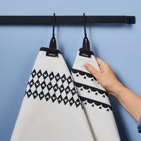 Two Kitchen Towels, adorned with subtle Mickey Mouse patterns, hang elegantly from a sleek black rail as someone holds them.