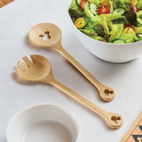 A salad, elegantly showcased with a 2-Piece Bamboo Salad Server Set, rests gracefully on a white tablecloth.