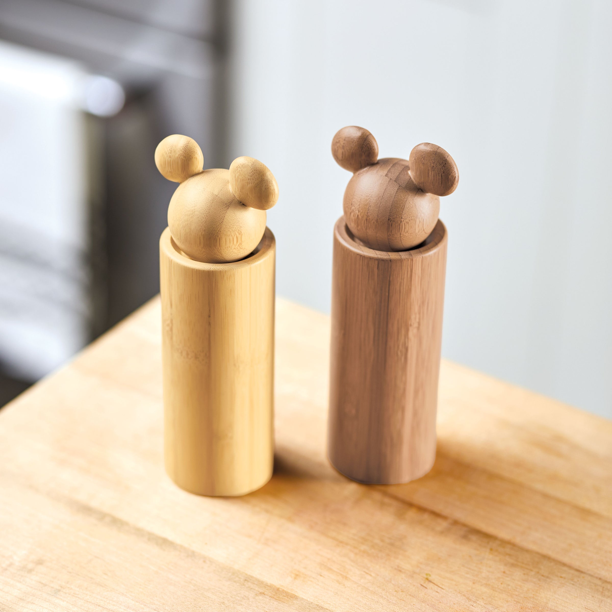 The Salt and Pepper Grinders with round handles are displayed on a wooden surface, bringing a touch of elegance to your Disney Home.