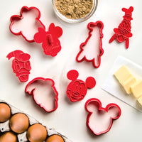 On the counter, a Bake with Mickey Mouse 8-Piece Cookie Cutter and Stamp Set waits alongside eggs and butter, perfect for making treats with Mickey and Friends.