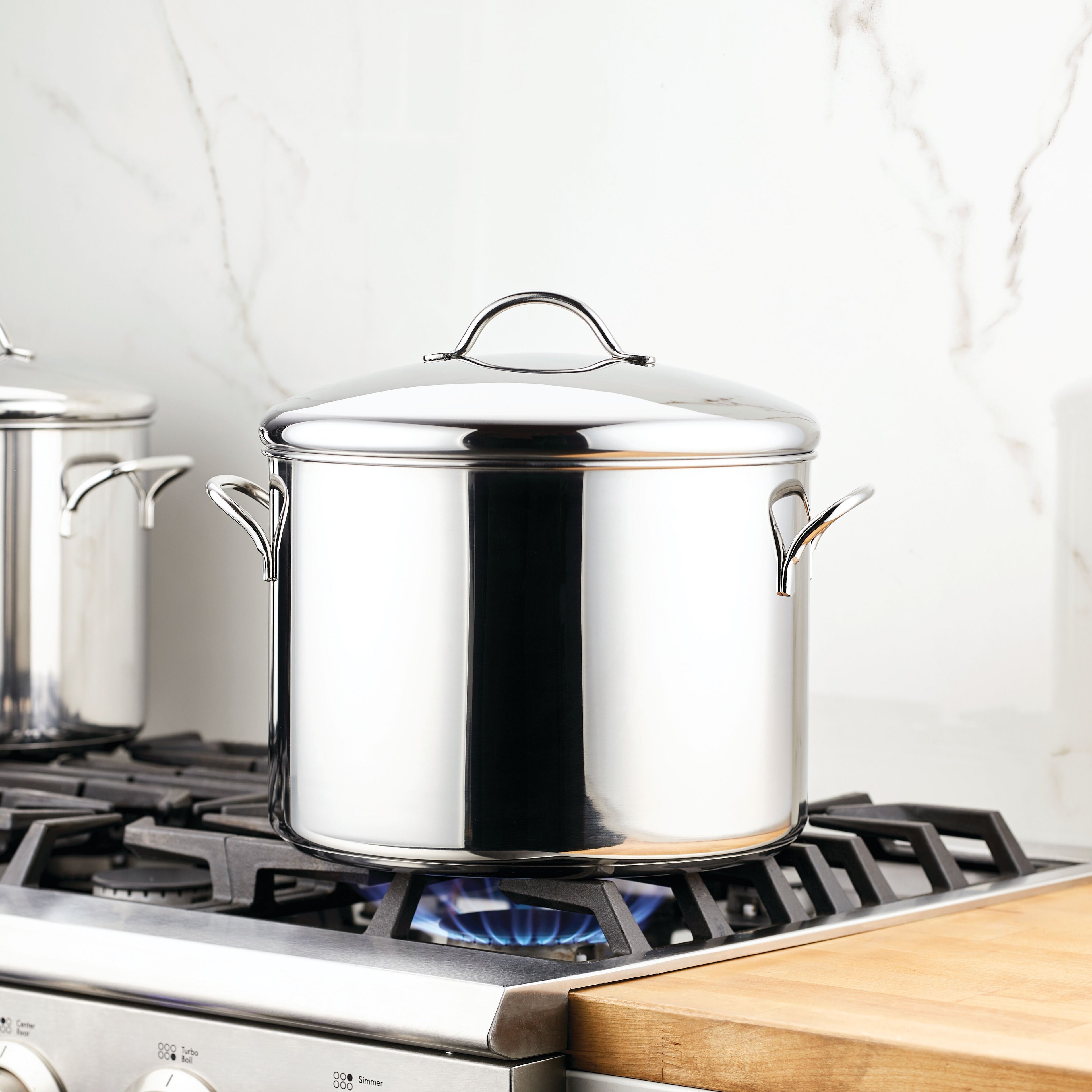 The Classic Series Stainless Steel Stockpot With Lid sits atop a lit gas stove, promising durability and long-lasting performance.