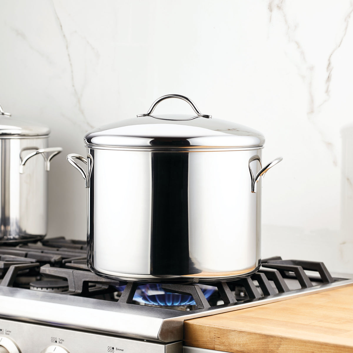 Stainless steel pot on a lit gas burner in a modern kitchen.