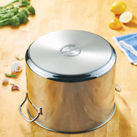 Stainless steel pot upside down on a wooden surface with vegetables nearby.