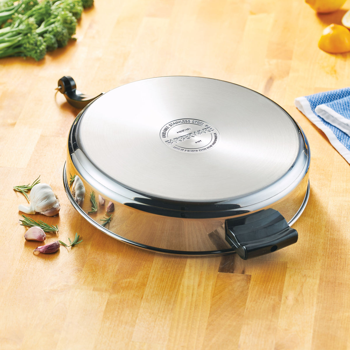 Round stainless steel pan lid on a wooden surface with some vegetables.