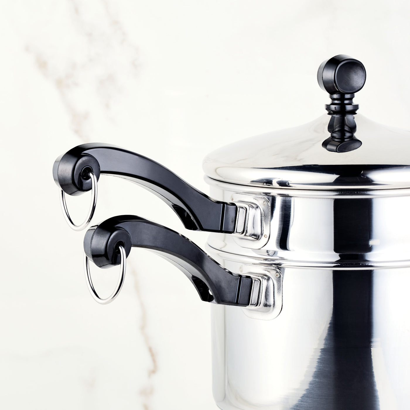 A stacked stainless steel saucepan with black handles featuring a matching self-basting lid, part of the Classic Series 2-Qt. Covered Saucepan with Double Boiler Insert.