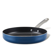 The 11.25-Inch Nonstick Deep Round Grill Pan, with its striking blue exterior and sleek silver handle, sits elegantly against a white background. This versatile piece of oven-safe cookware ensures effortless cooking and easy cleanup every time.