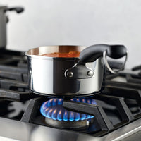 A pot of food is simmering on a gas stove burner, nestled in the 1-Quart Stainless Steel Saucepan, perfect for everyday cooking.
