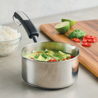 A pot of green curry with vegetables sits invitingly next to fragrant rice, fresh lime, and chopped chili, perfectly showcasing the art of everyday cooking in a 1-Quart Stainless Steel Saucepan.