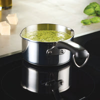 The 1-Quart Stainless Steel Saucepan filled with green sauce simmers on the induction cooktop, perfect for everyday cooking.