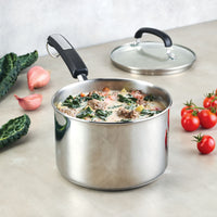 A 3-Quart Stainless Steel Saucepan, filled with creamy soup, kale, and sausage, rests gracefully with its lid and fresh vegetables nearby.