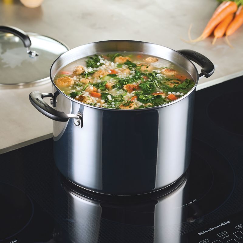 An 8-Quart Stainless Steel Stockpot simmers soup with veggies and meatballs.