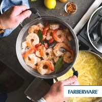A person uses a 10 Inch Steamer Insert Stainless Steel to cook shrimp with bay leaves.