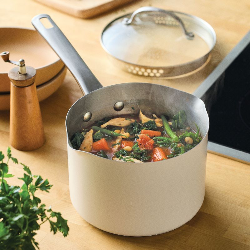 A 3-Quart Straining Saucepan with Lid sits on a wooden kitchen counter.