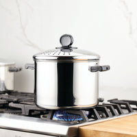 Stainless steel pot on a lit stove burner with a lid.