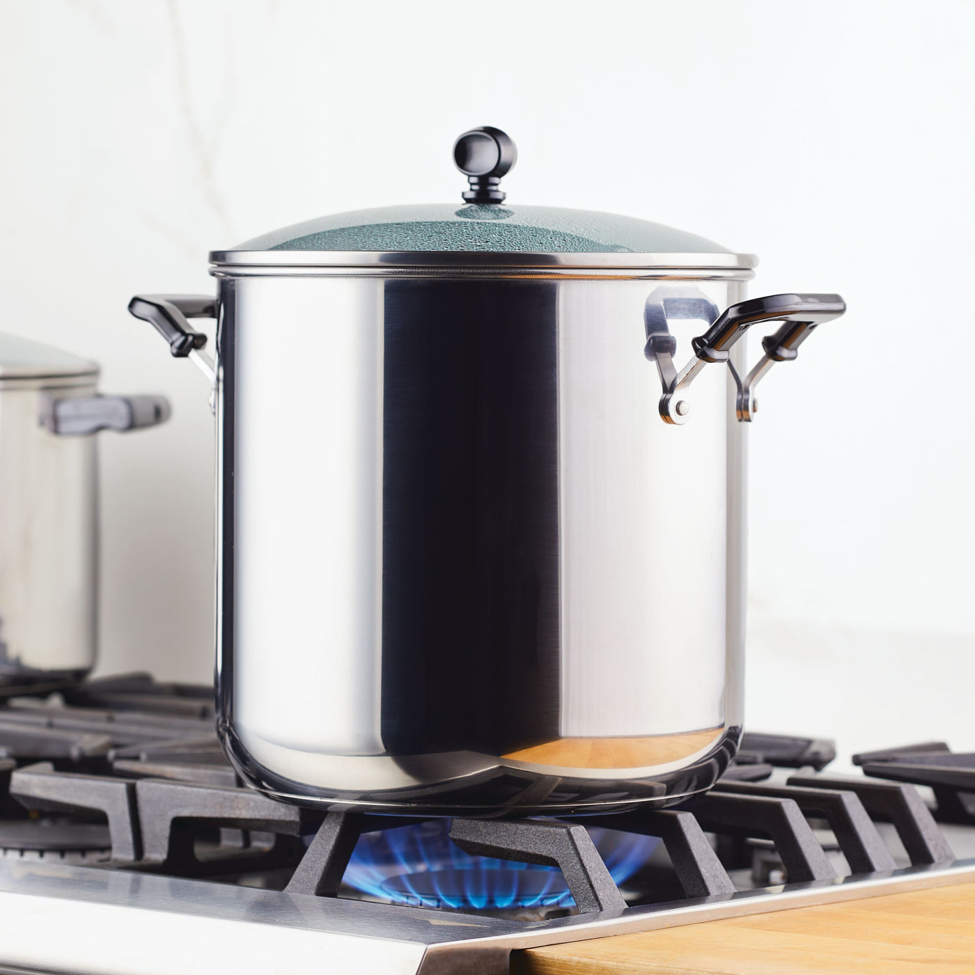 The Classic Series Stainless Steel 11-Qt. Stockpot With Lid sits elegantly on the gas stove flame, promising long-lasting performance for all your cooking needs.
