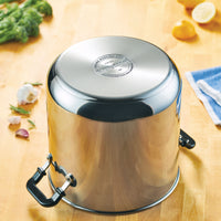 The Classic Series Stainless Steel 11-Qt. Stockpot with Lid is upside down on the wooden countertop, surrounded by vibrant vegetables, ensuring long-lasting performance and exceptional durability for your culinary endeavors.