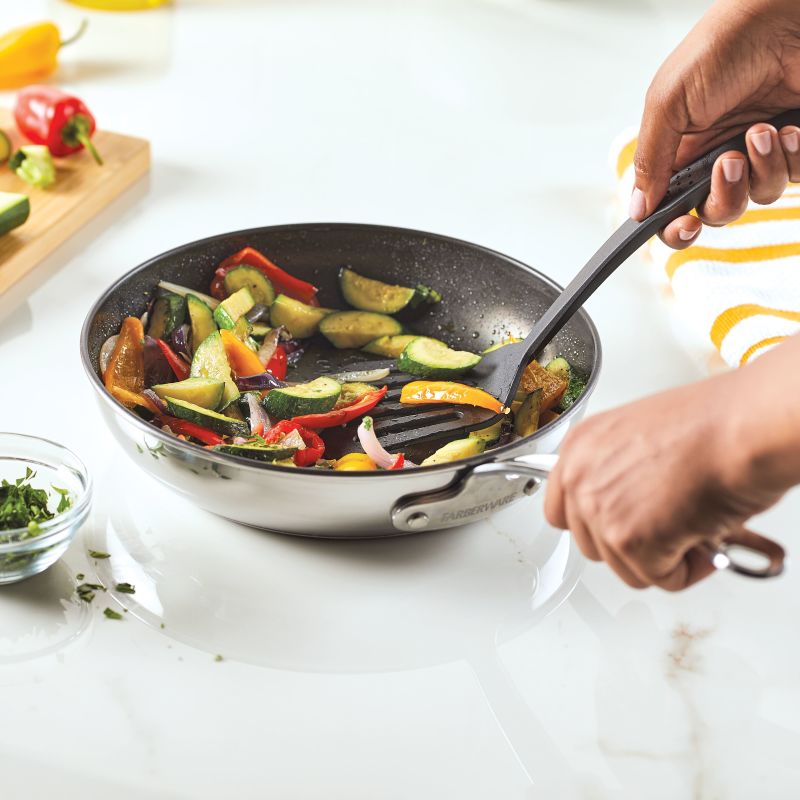 Person sautéing vegetables in Millennium Nonstick Stainless Steel 10-Piece Set.