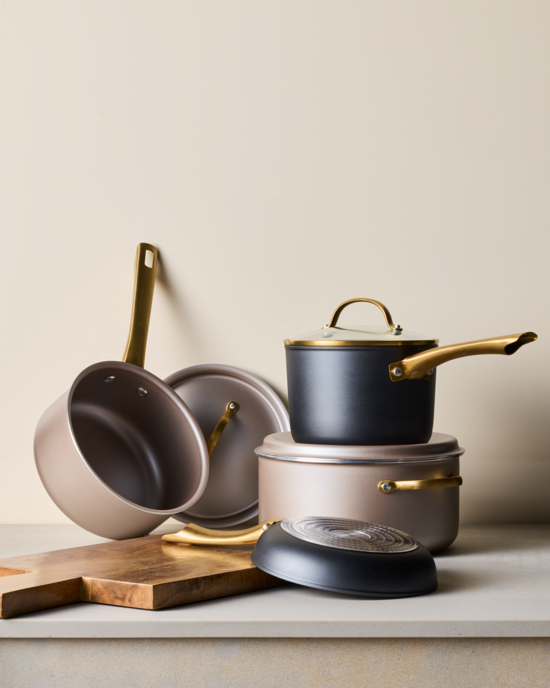 Radiant and Forged Induction Cookware stacked next to a wooden cutting board