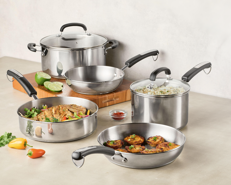 A set of stainless steel cookware with food displayed on a kitchen surface.