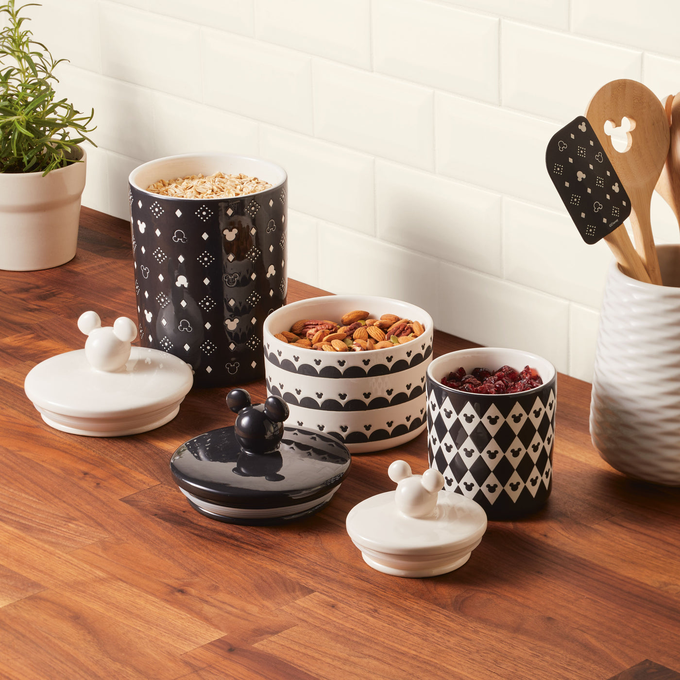 A 3 Piece Set of Ceramic Jars with Airtight Lids sits on a wooden counter, adding charm to your kitchenware collection.