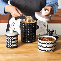 An individual is scooping oats from a canister in the 3 Piece Set of Ceramic Jar with Airtight Lids, featuring a Disney Mickey Mouse design as part of an enchanting kitchenware collection, complete with a white lid.