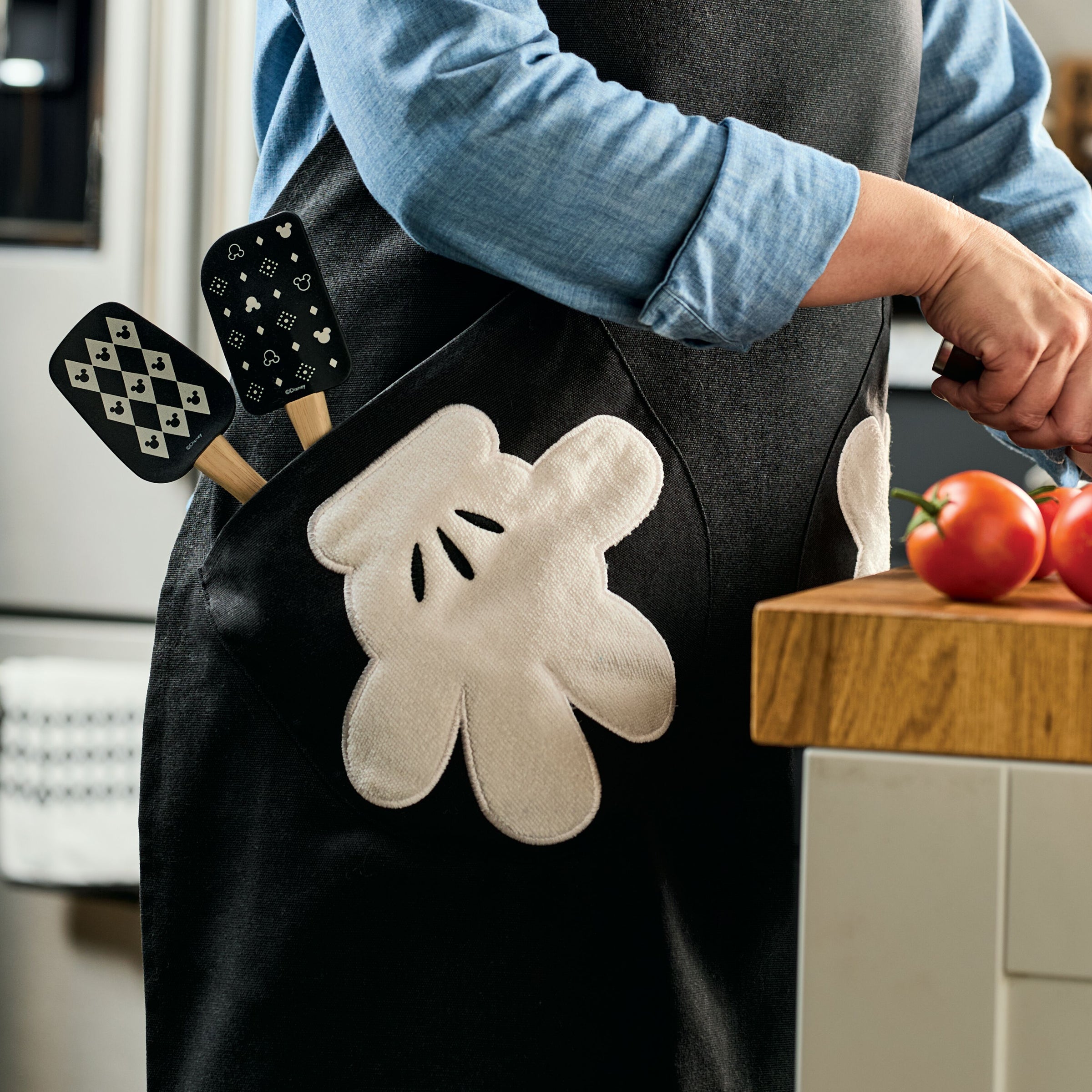 Wearing an Apron with Glove Pockets, a person expertly chops tomatoes, with spatulas neatly tucked into the pockets.