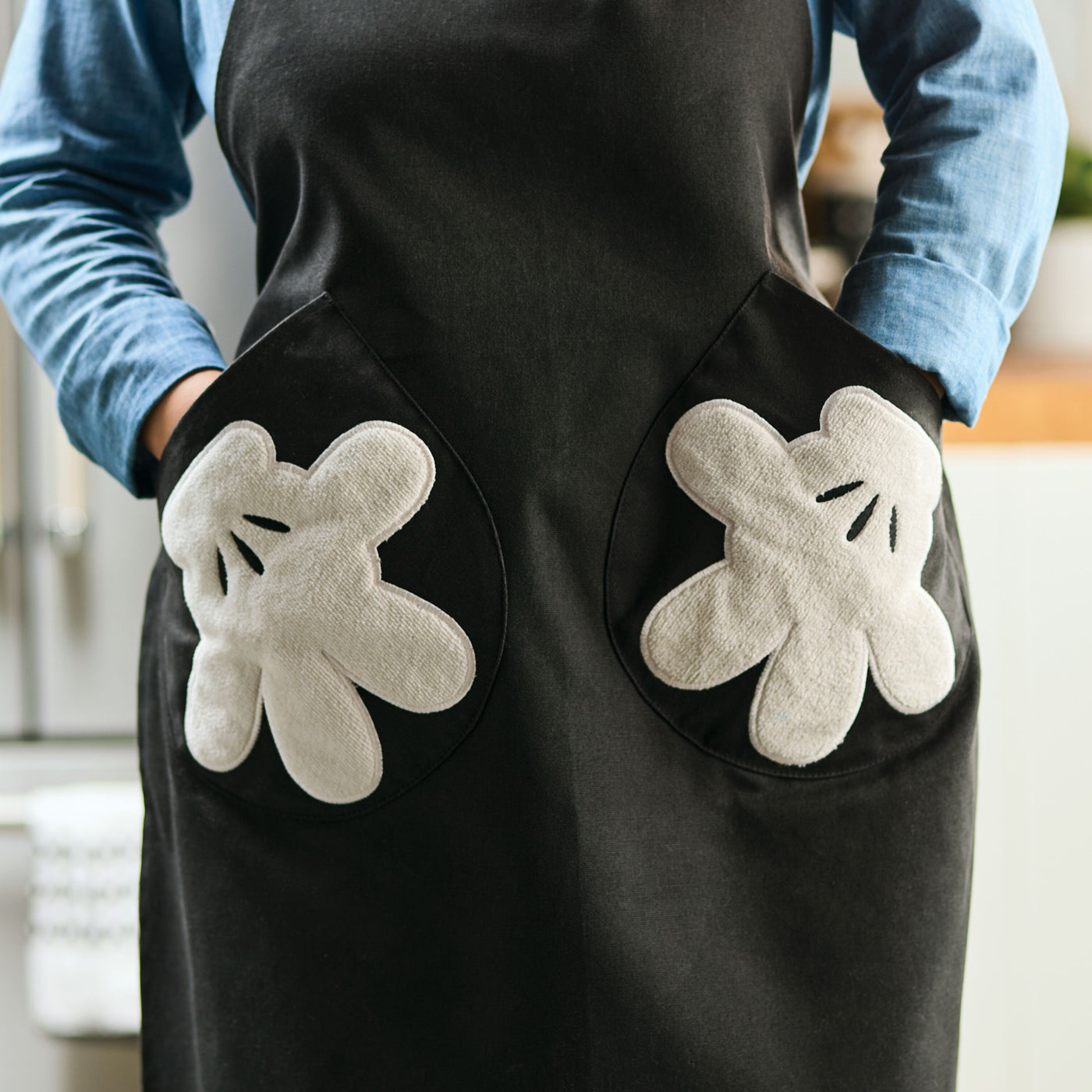 The Monochrome 5-Piece Set includes a delightful apron with cartoon glove-style pockets, reminiscent of the beloved Mickey Mouse design, making it a charming addition to your Disney Home kitchen set.