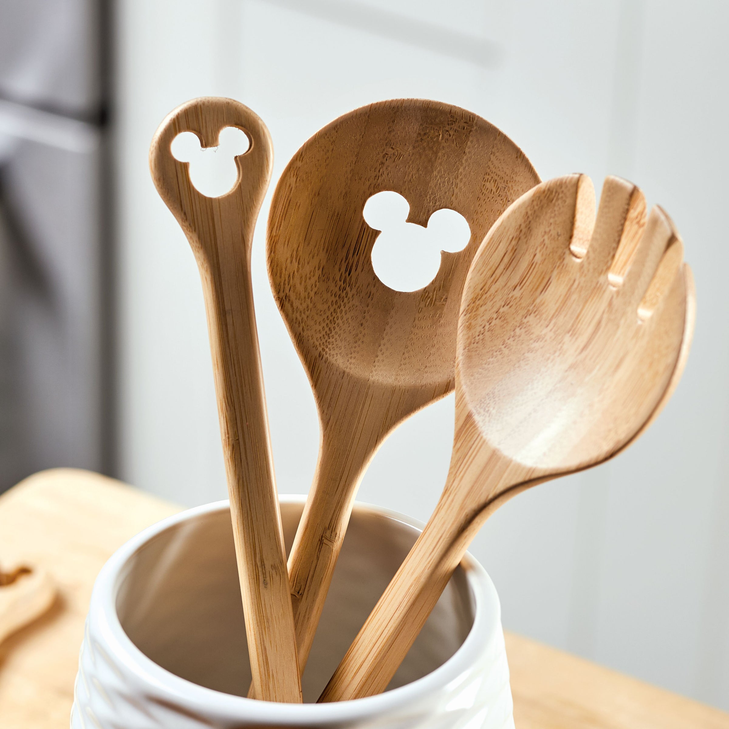 Explore the Disney Home Monochrome collection, which includes the delightful 2-Piece Bamboo Salad Server Set with wooden kitchen utensils featuring Mickey Mouse cutouts in a pristine white container.