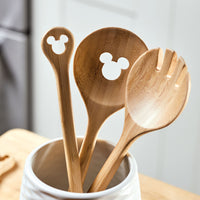 The Monochrome Kitchen Tool Set features three wooden utensils with delightful Mickey Mouse cutouts, elegantly displayed in a white holder that's perfect for any Disney-themed kitchen.
