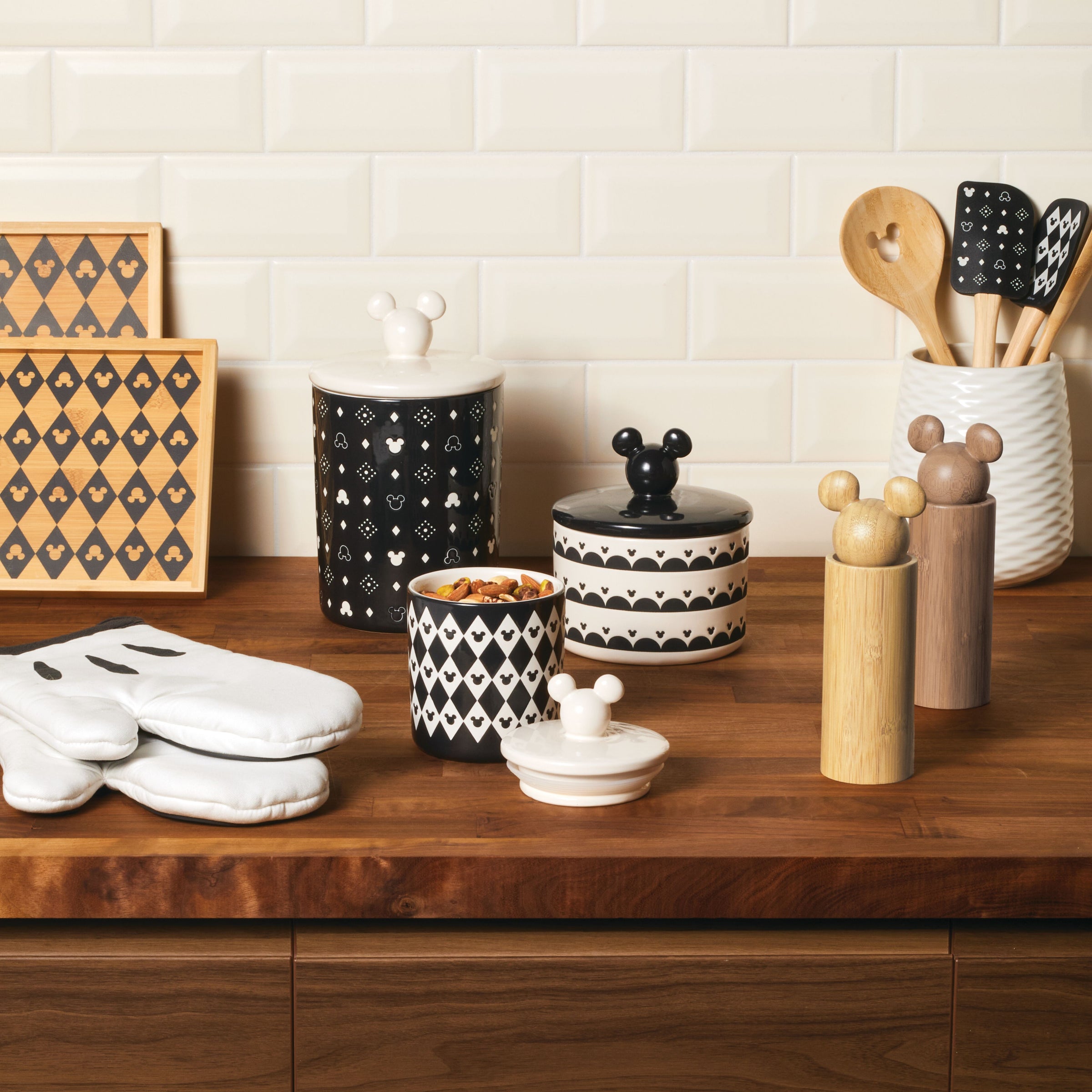 The 3 Piece Set of Ceramic Jars with Airtight Lids in black and white is elegantly displayed on a wooden countertop, capturing the timeless allure of Disney's Mickey Mouse style.