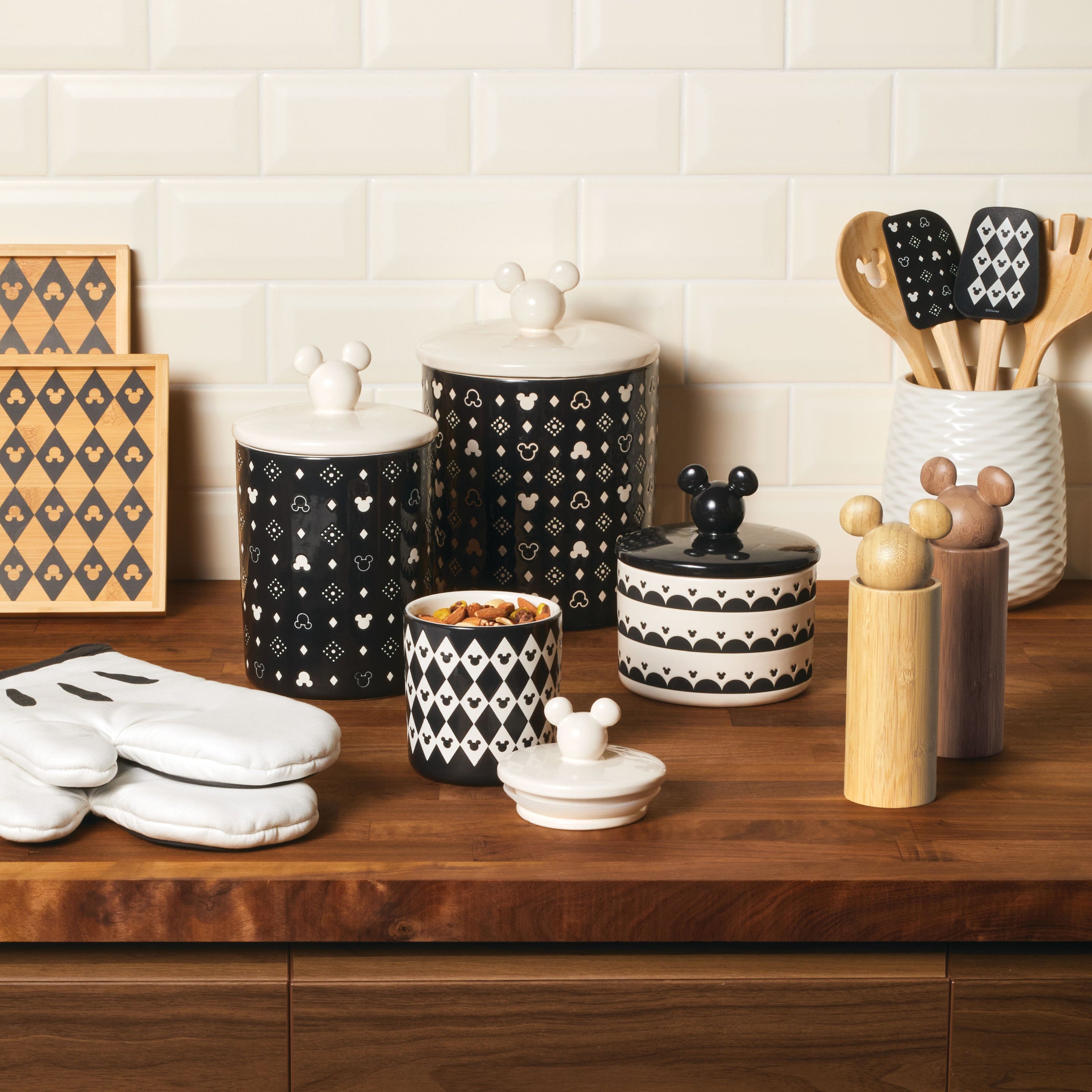 A charming kitchen counter is adorned with decorative containers, including the Ceramic Jar with Airtight Lid that features Disney's Mickey Mouse, equipped and ready with cooking utensils. The airtight lid ensures freshness while adding a touch of whimsy to your culinary space.
