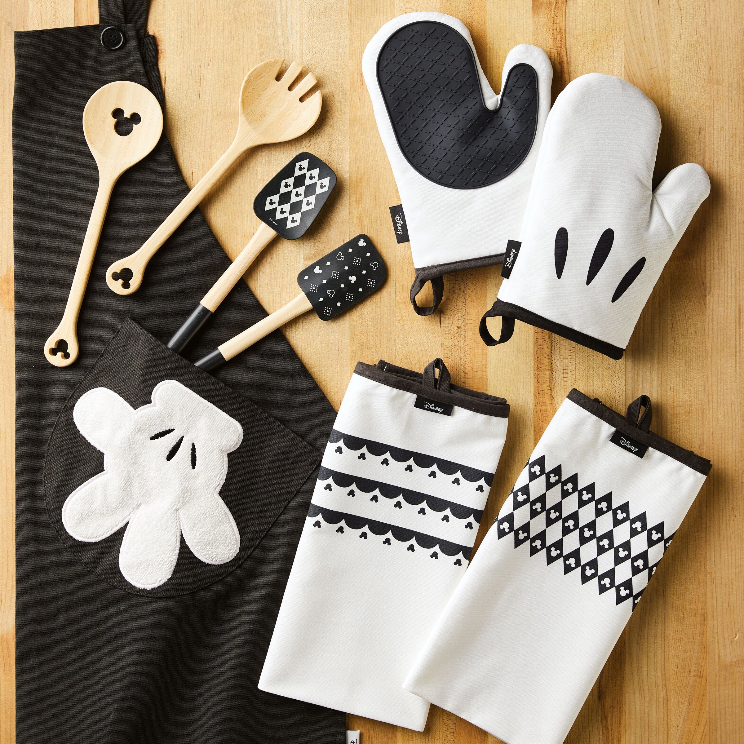 Explore the Mickey Mouse themed kitchen set from the Disney Home Monochrome collection, featuring a stylish two-piece bamboo salad server set on a table. Perfect for adding charm to your culinary adventures!