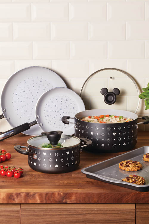 Black pots and pans on a kitchen counter with cookies and cherry tomatoes.