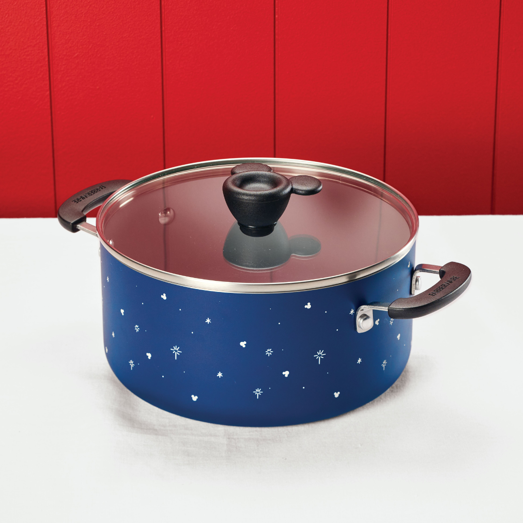 Blue pot with a glass lid on a white surface, red wall background.